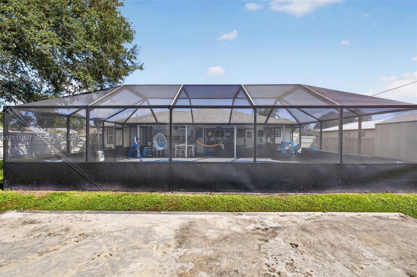 Screen-enclosed outdoor space featuring a covered patio, concrete flooring, and a fenced backyard