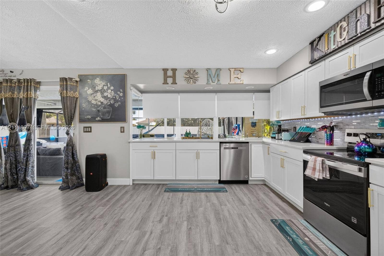 Kitchen featuring white cabinetry with gold-tone hardware, stainless steel appliances, wood-finish flooring, and recessed lighting