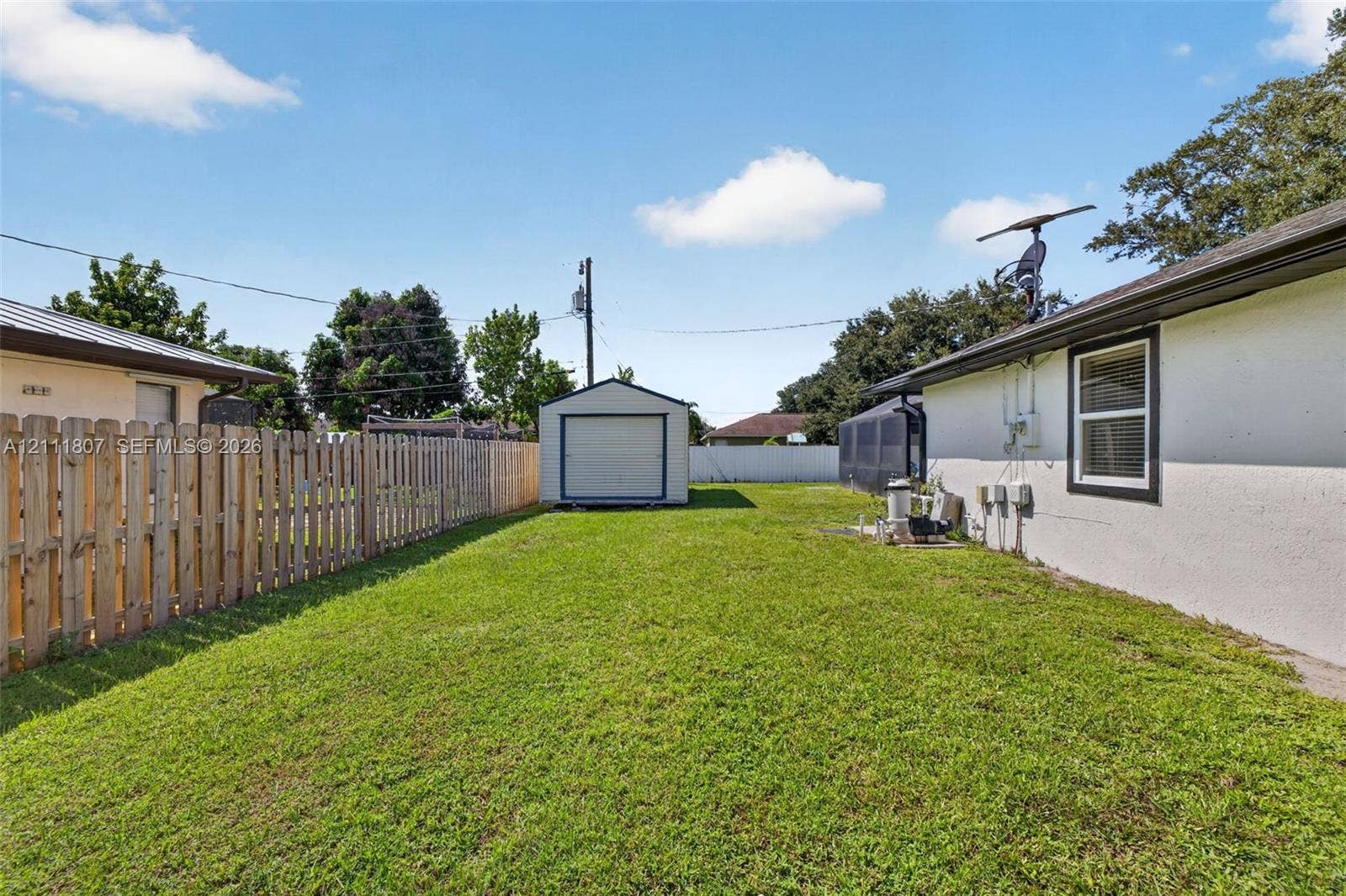 Backyard featuring a grass lawn, perimeter wood fence, and a detached storage shed