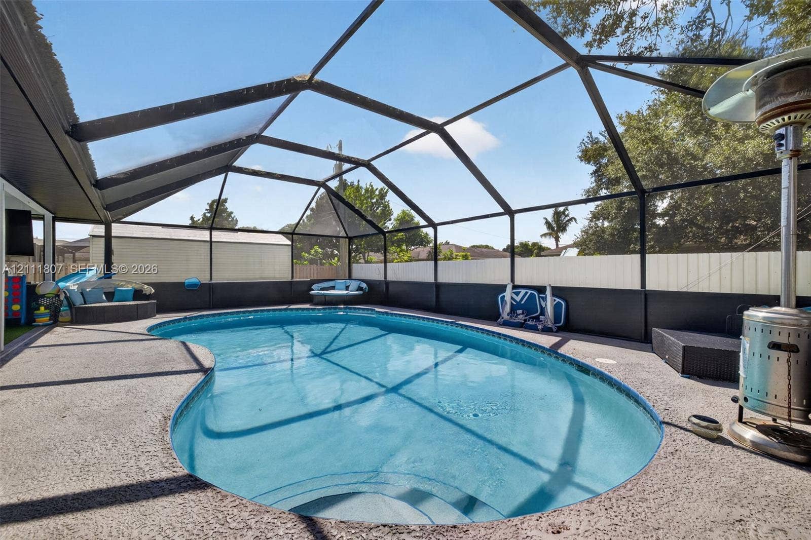 Screen-enclosed pool featuring a pebble-finish deck, molded stairs, and solid perimeter fencing