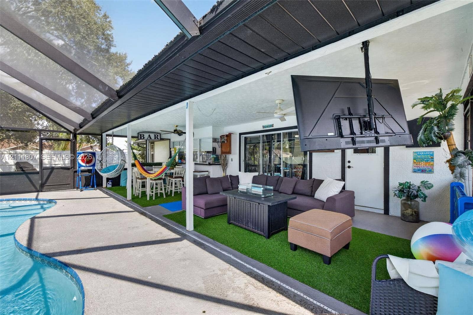 Screened lanai featuring a concrete deck, built-in bar, ceiling fans, and an attached swimming pool