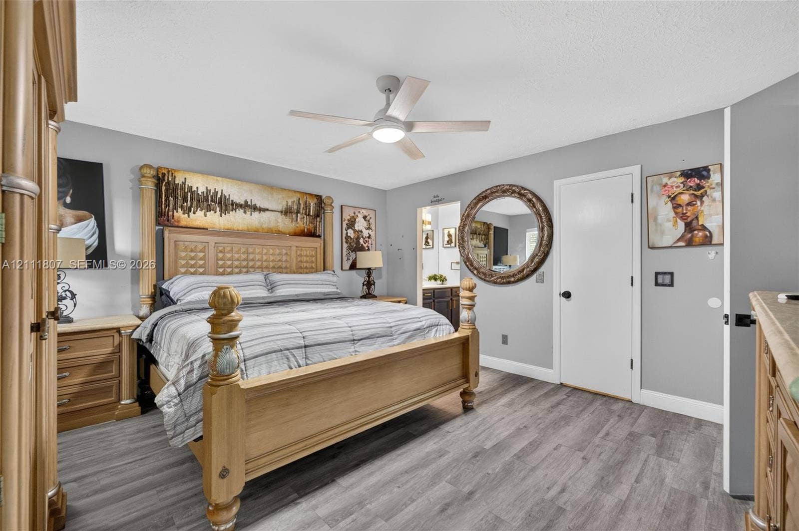 Room featuring wood-finish flooring, a ceiling fan with integrated lighting, and a circular wall mirror