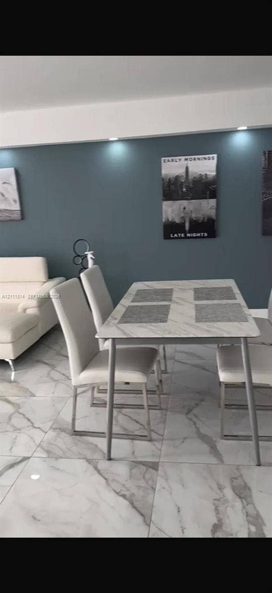 Large-format tile flooring with a neutral-toned veined pattern, accent wall featuring recessed ceiling lighting, and crisp white trim