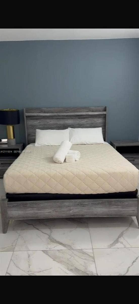 Room featuring large-format, stone-finish floor tile and a solid-color accent wall