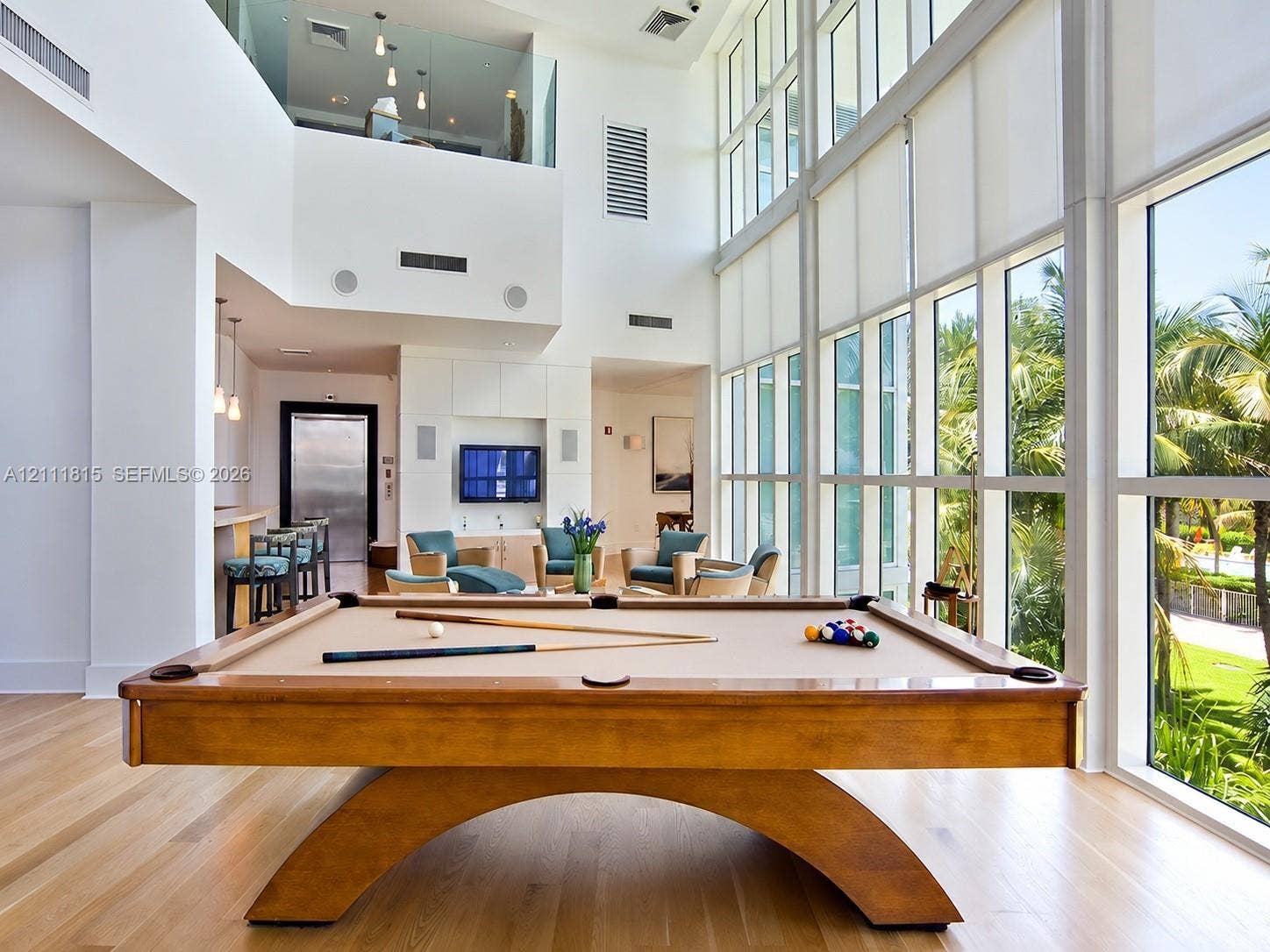 15811 Collins Avenue, #4102, Sunny Isles Beach, FL 33160 Double-height ceiling, floor-to-ceiling windows, wood-finish flooring, built-in wet bar, and glass-paneled mezzanine railing
