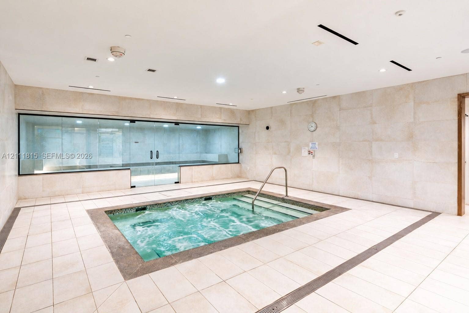 15811 Collins Avenue, #4102, Sunny Isles Beach, FL 33160 Indoor spa room featuring a tiled plunge pool, recessed lighting, expansive wall-to-wall glass enclosure, and stone-finish wall cladding