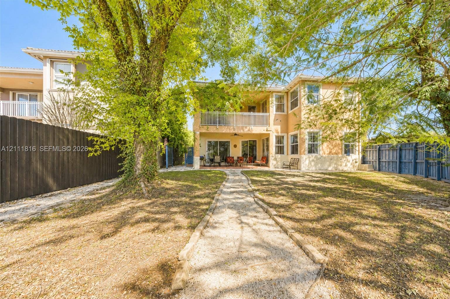 Exterior backyard featuring a gravel walkway, multi-level balconies with metal railings, and fenced perimeter