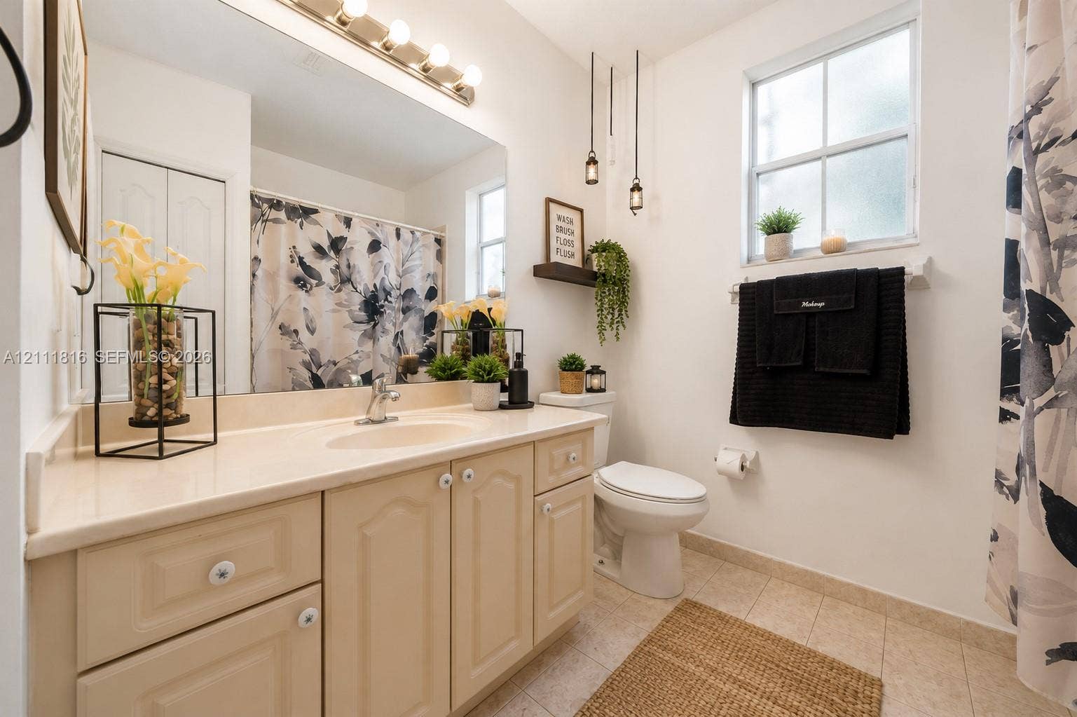 Bathroom featuring a vanity with integrated sink and countertop, large wall-mounted mirror, multi-light vanity fixture, pendant lighting, and ceramic tile flooring