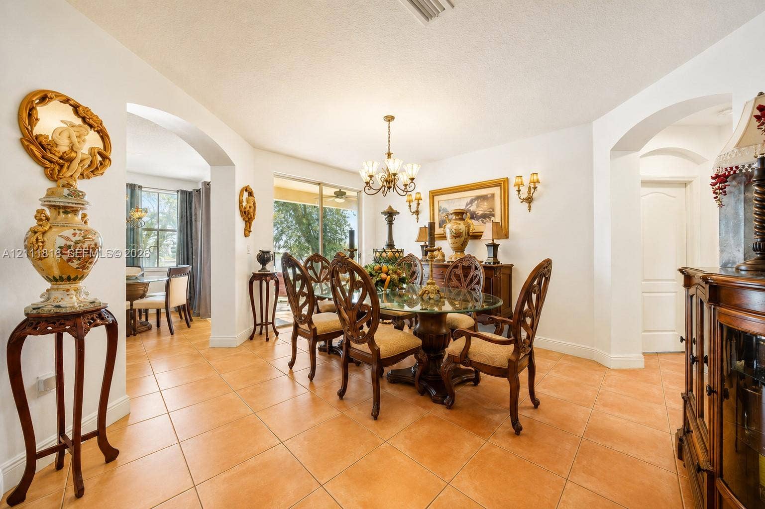 Ceramic tile flooring, arched entryways, multi-tiered chandelier, and glass sliding doors