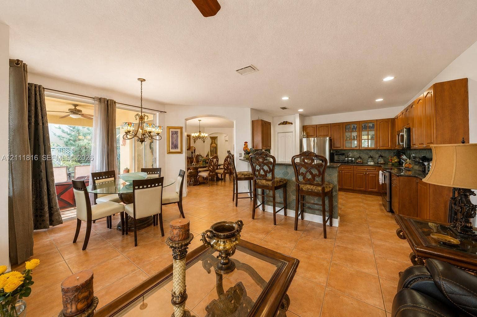 Open-concept living space featuring ceramic tile flooring, recessed lighting, and a kitchen equipped with wood cabinetry and an integrated breakfast bar