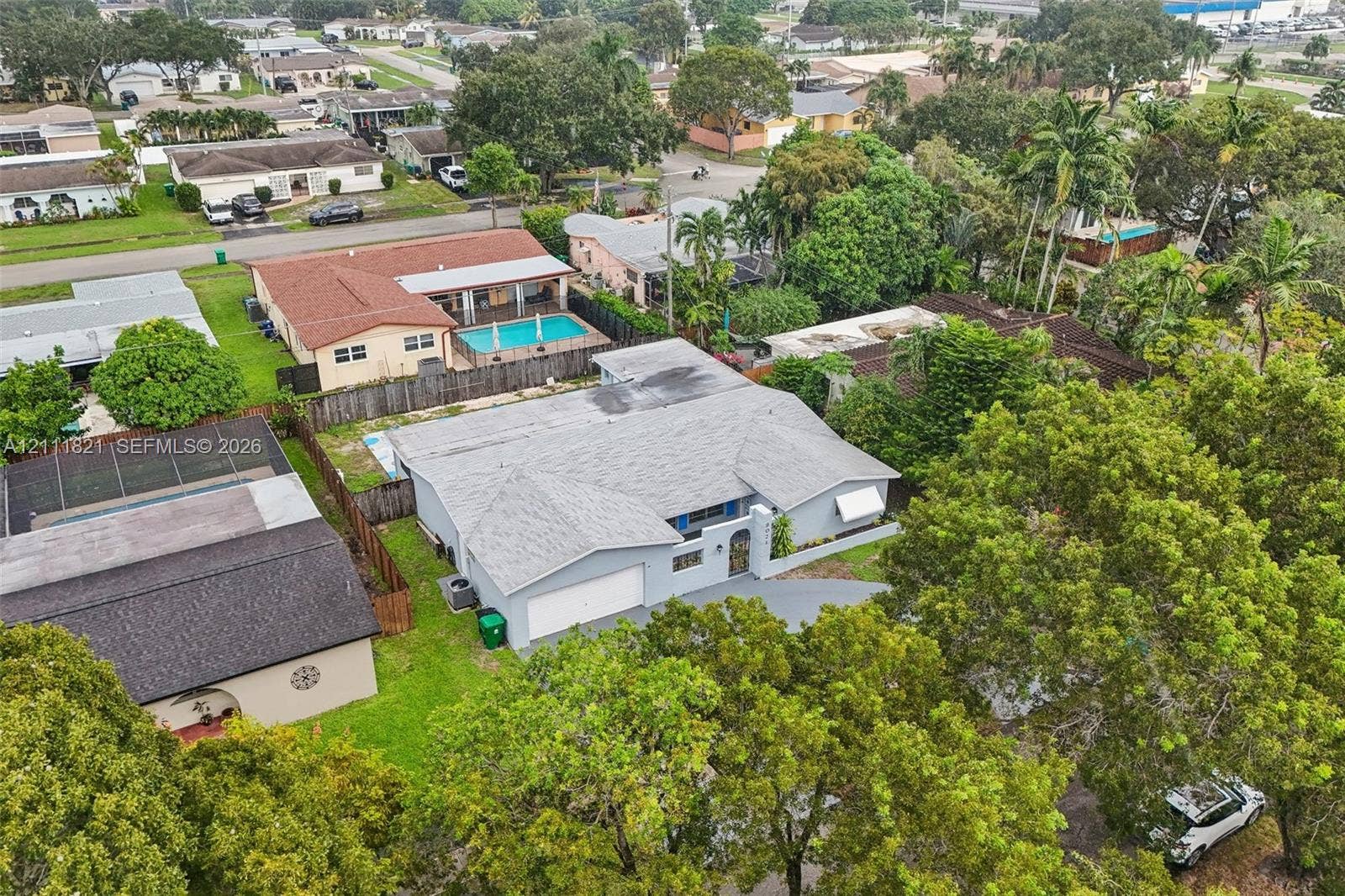 Single-story residence featuring a gray stucco exterior, multi-gabled shingle roof, attached two-car garage, and established landscaping