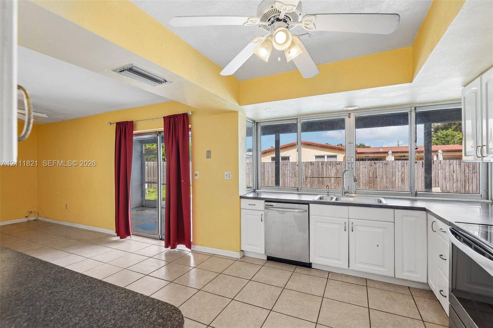 Kitchen featuring white cabinetry, stainless steel dishwasher, tile flooring, ceiling fan with light fixture, and a picture window