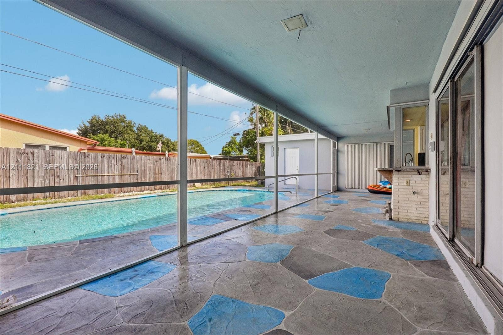 Screened-in lanai featuring a stamped concrete floor, built-in masonry bar, and a private swimming pool
