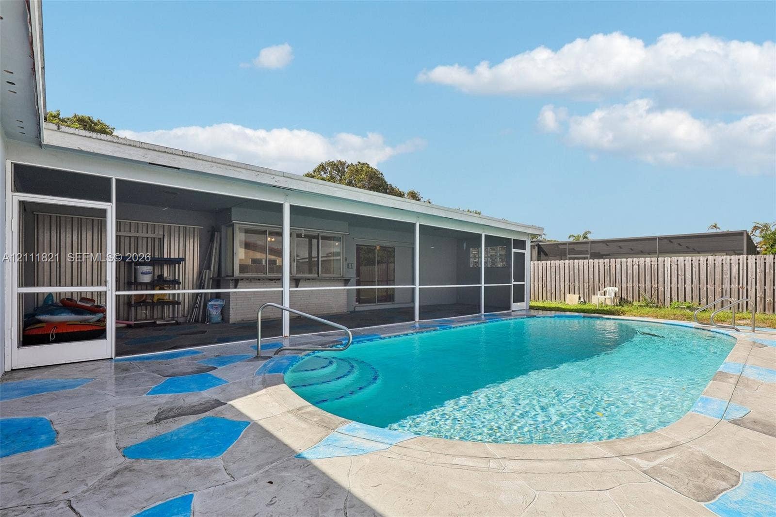 Screened-in patio featuring a concrete pool deck, in-ground swimming pool with steps, and full-perimeter privacy fencing