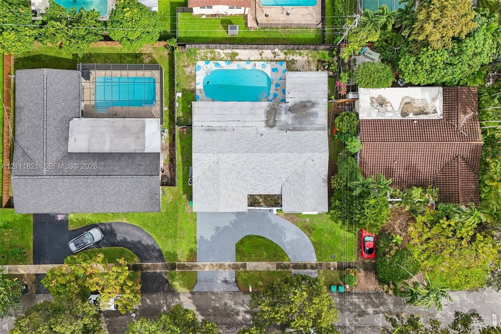 Aerial perspective featuring a residential property with a swimming pool, concrete hardscaping, and mature landscaping