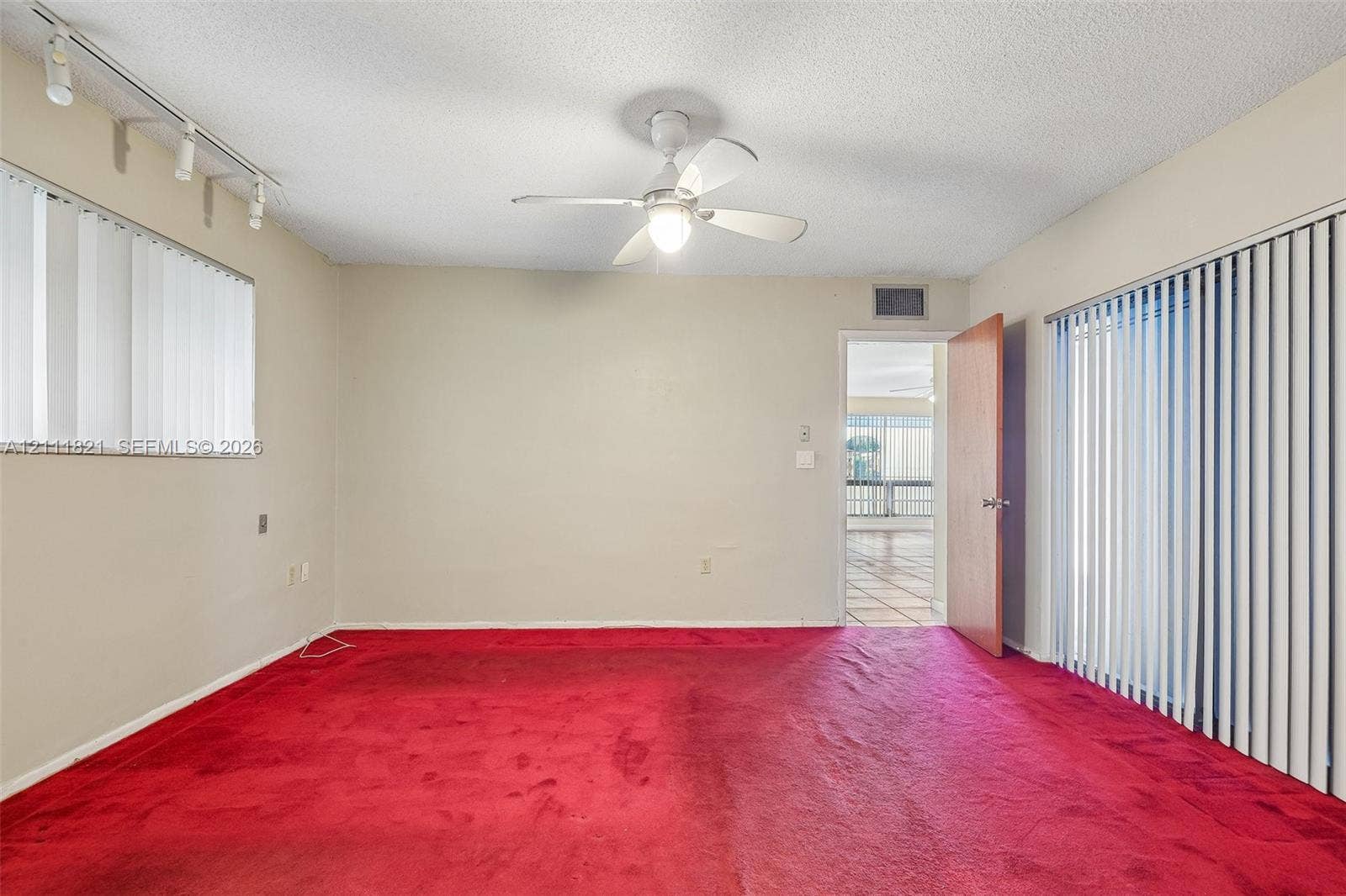 Interior room featuring carpet flooring, ceiling fan with integrated lighting, track lighting, and vertical window blinds