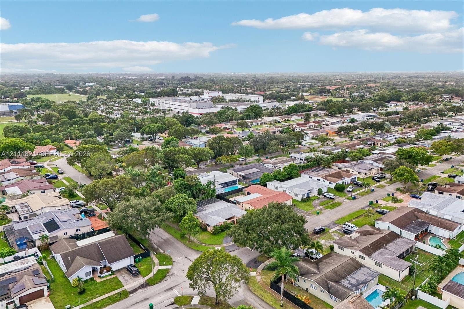 Aerial perspective of a residential neighborhood featuring mature trees, landscaped lawns, and established street infrastructure