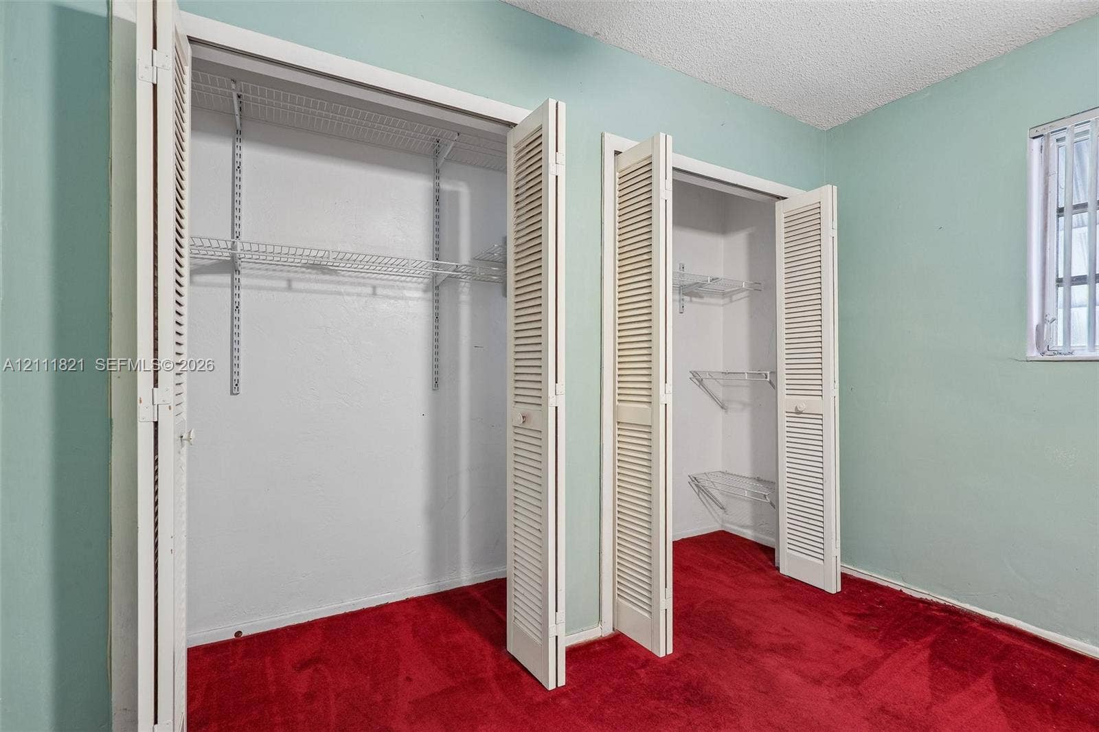 Dual closets featuring white louvered bifold doors, adjustable wire shelving, and wall-to-wall carpeting