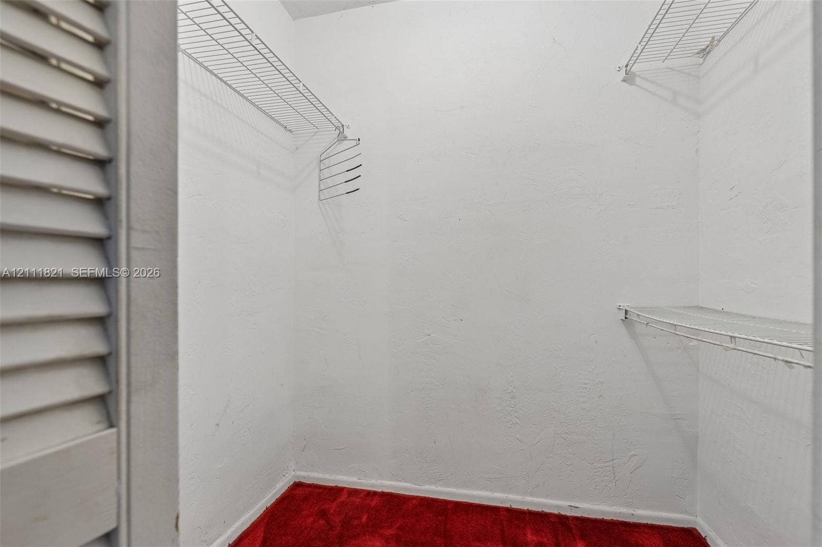 Storage closet featuring white walls, carpet flooring, and dual-level wire shelving