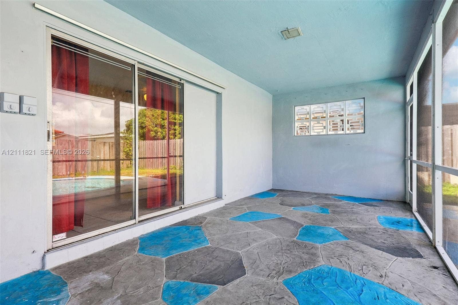 Enclosed porch featuring flagstone-patterned concrete flooring, sliding glass door, glass block window, and screen wall panels