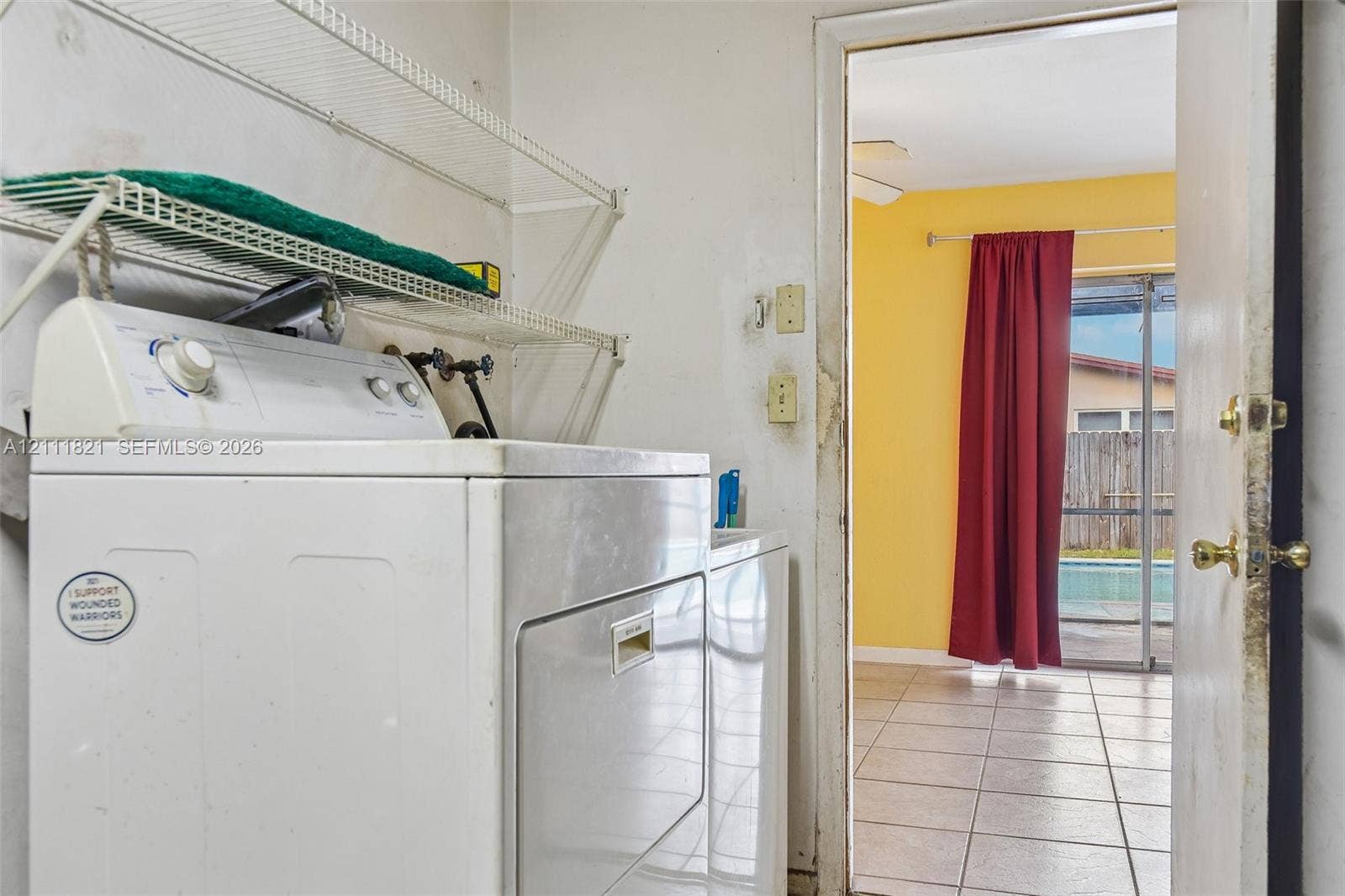 Utility area featuring white wire wall-mounted shelving and tile flooring