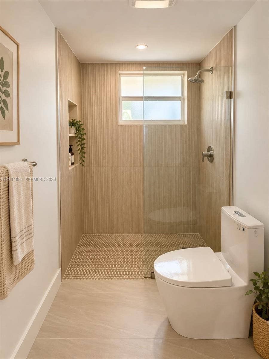 1629 N River Drive, #103, Miami, FL 33125 Walk-in shower with floor-to-ceiling textured tile, integrated recessed shelving, frameless glass enclosure, penny-round mosaic tile shower floor, and a wall-mounted shower head