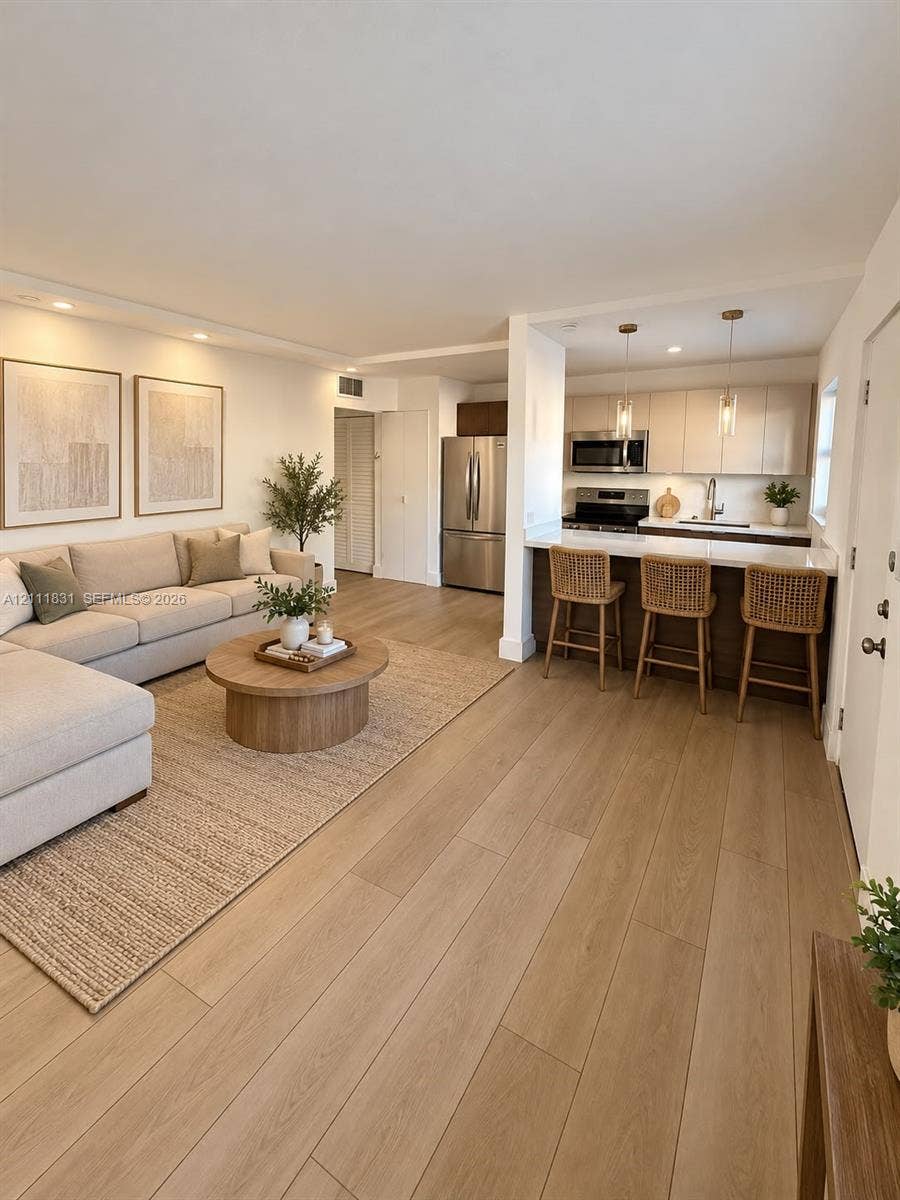 1629 N River Drive, #103, Miami, FL 33125 Open-concept interior featuring light wood-finish flooring, recessed lighting, and a kitchen with stainless steel appliances, flat-panel cabinetry, and a breakfast bar