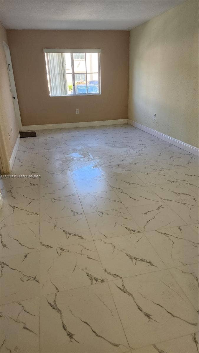 1250 SE 28th Court, #102, Homestead, FL 33035 Large-format, veined tile flooring throughout, neutral interior wall paint, and a single-pane window