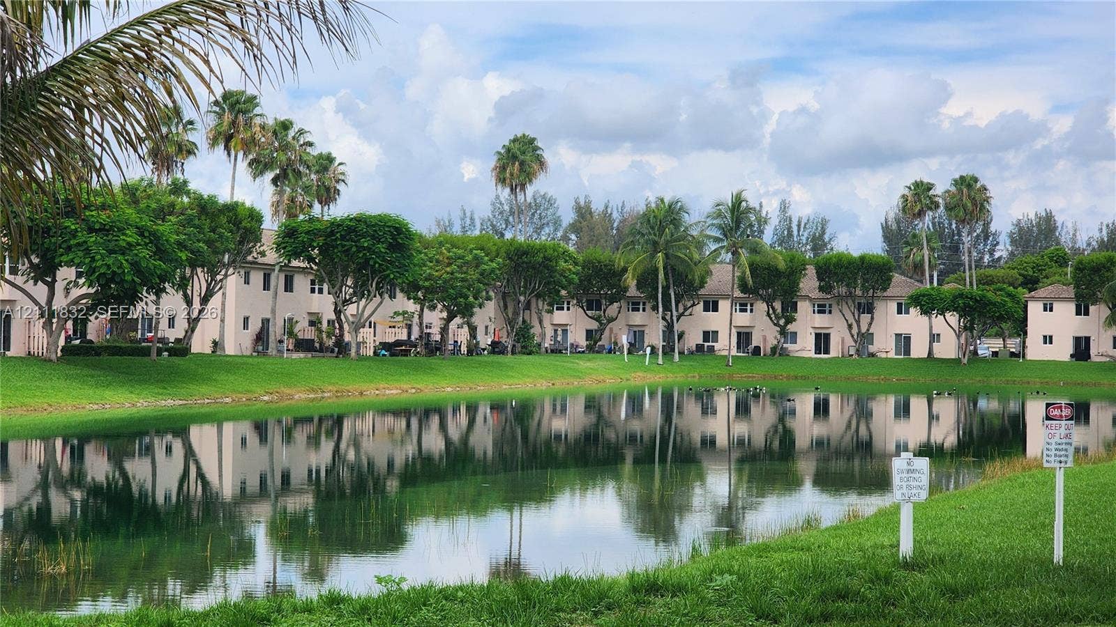 1250 SE 28th Court, #102, Homestead, FL 33035 Waterfront exterior featuring a central pond, manicured lawn, and established palm trees