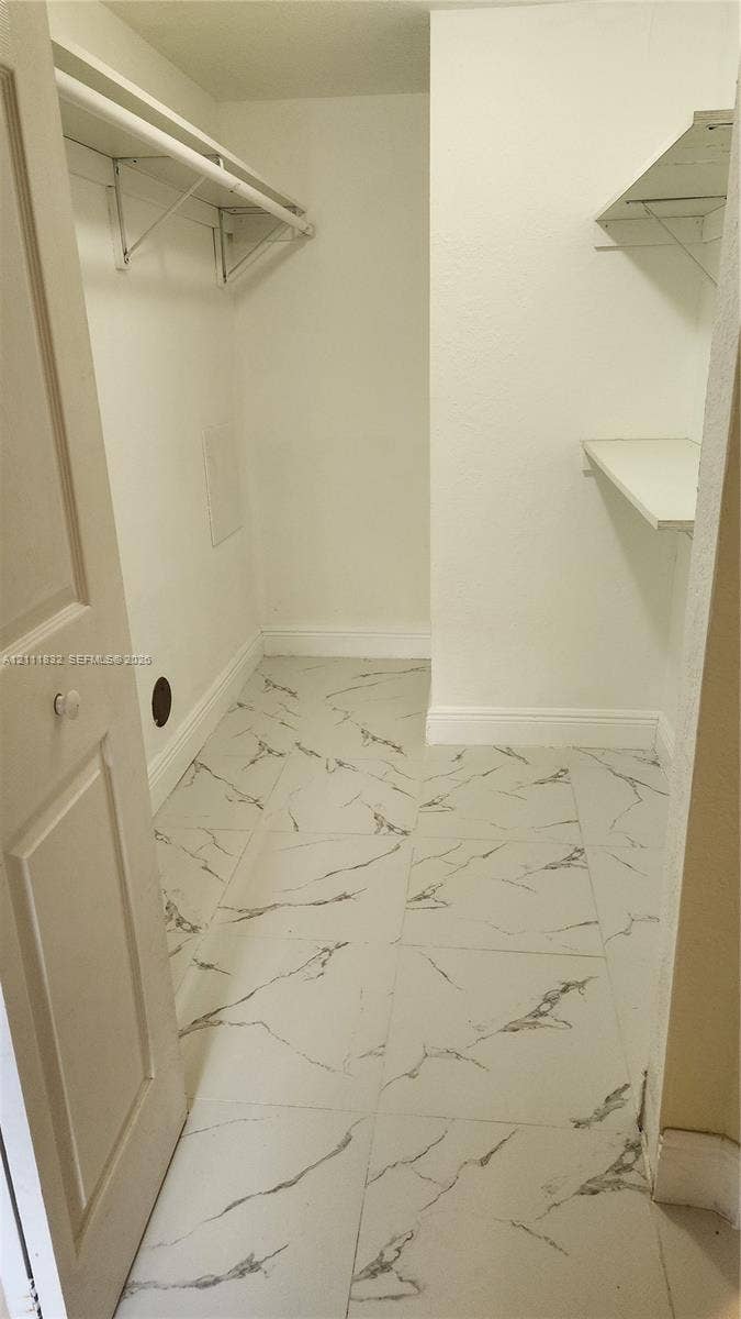1250 SE 28th Court, #102, Homestead, FL 33035 Walk-in closet featuring stone-finish floor tiling and multi-level built-in shelving
