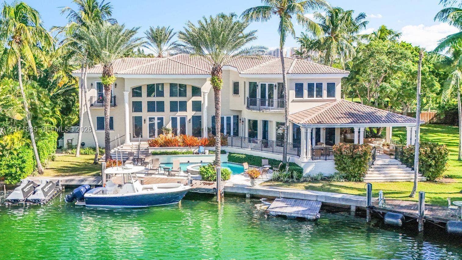 Two-story waterfront residence featuring a tile roof, private boat dock, swimming pool with integrated spa, and covered terrace
