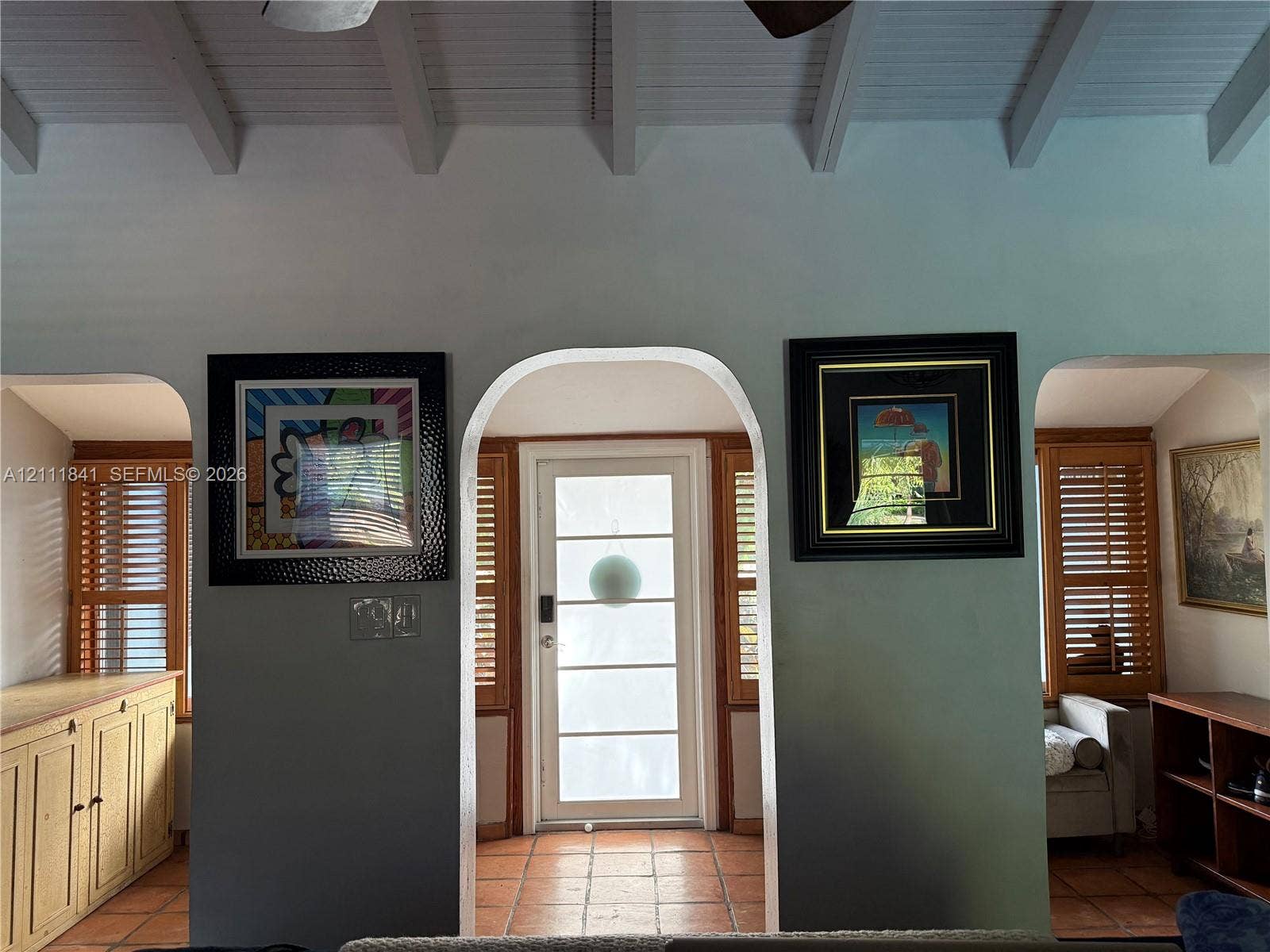 12015 NE 6th Avenue, Biscayne Park, FL 33161 Exposed beamed ceiling with white finish, terracotta tile flooring, arched doorways, and natural wood louvered shutters