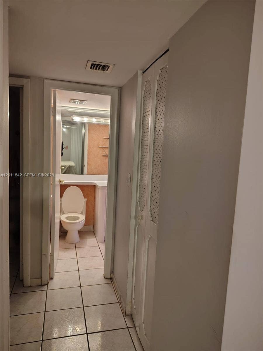 20400 W Country Club Drive, #303, Aventura, Aventura, FL 33180 Hallway featuring light-toned ceramic tile flooring and bi-fold closet doors with decorative perforated metal panels
