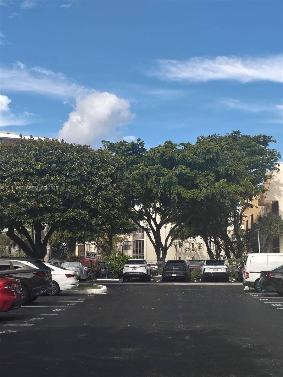 20400 W Country Club Drive, #303, Aventura, Aventura, FL 33180 Asphalt parking lot featuring painted stall markings and mature canopy trees