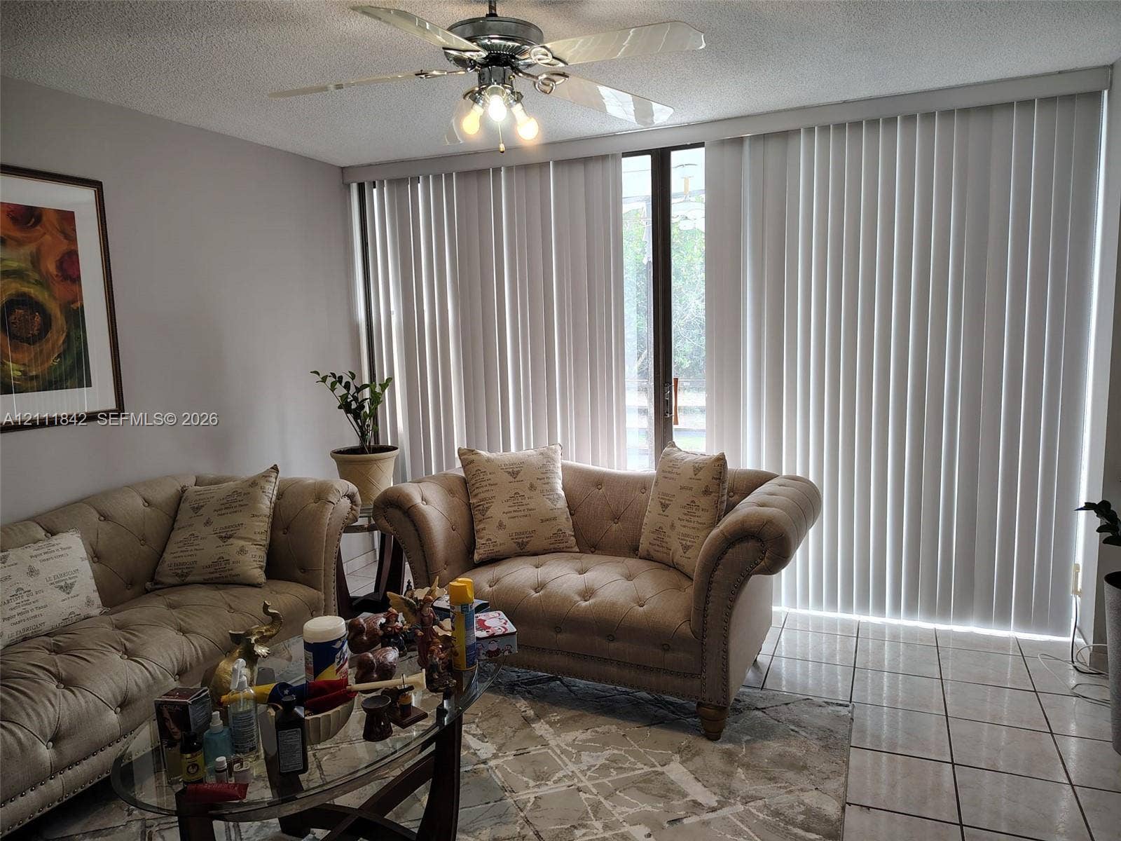 20400 W Country Club Drive, #303, Aventura, Aventura, FL 33180 Living area featuring large-format ceramic tile flooring, floor-to-ceiling vertical blinds, and a central ceiling fan with integrated lighting