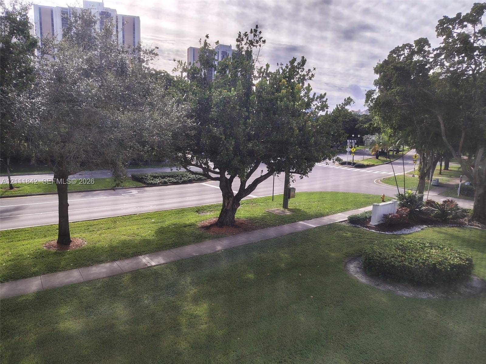 20400 W Country Club Drive, #303, Aventura, Aventura, FL 33180 Expansive green space featuring mature trees, manicured lawn, concrete sidewalk, and landscaped garden beds