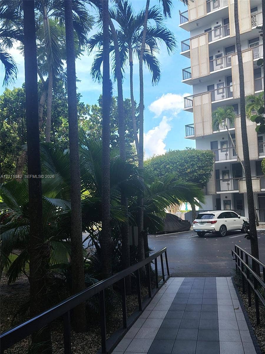 20400 W Country Club Drive, #303, Aventura, Aventura, FL 33180 Exterior walkway featuring patterned tile paving, metal railings, and mature palm tree landscaping