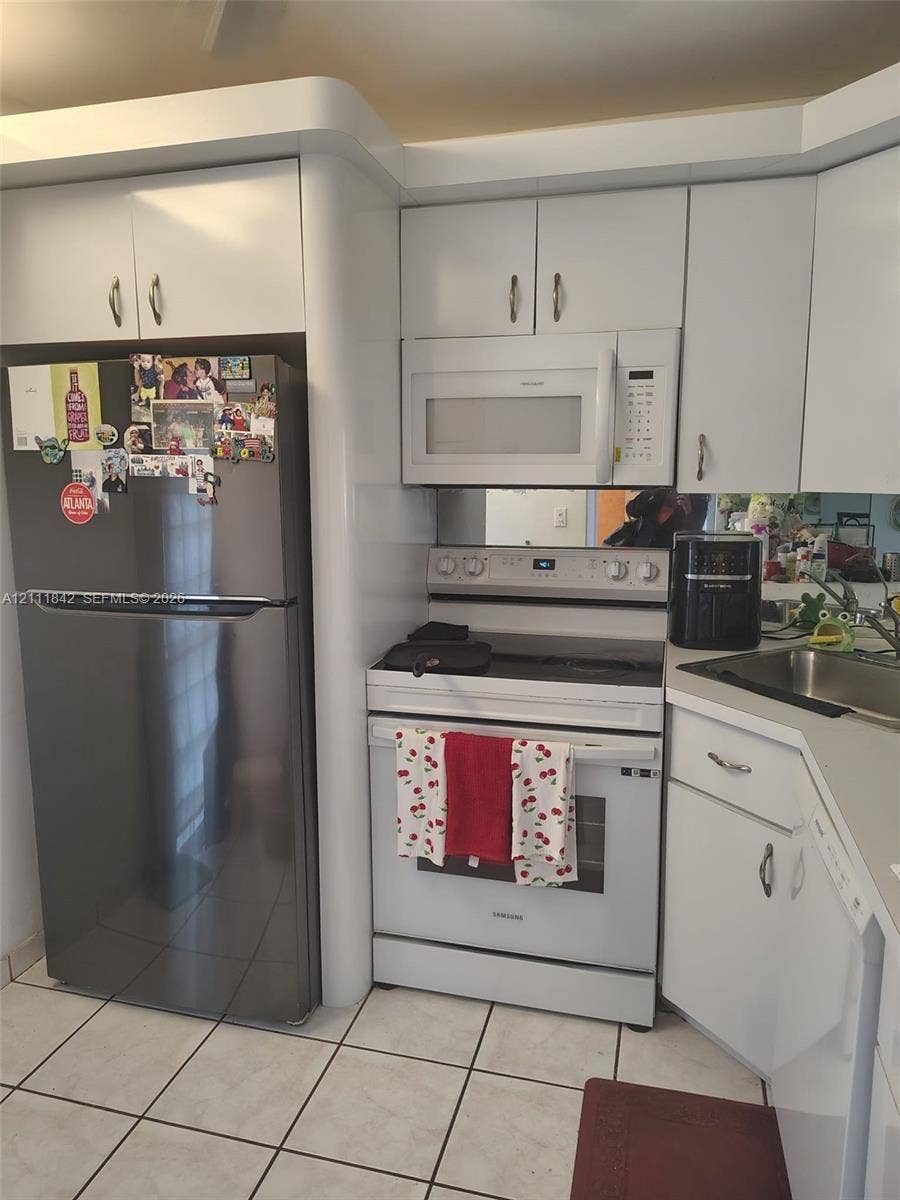 20400 W Country Club Drive, #303, Aventura, Aventura, FL 33180 Kitchen featuring white cabinetry, stainless steel refrigerator, white electric range with over-the-range microwave, integrated mirror backsplash, and tile flooring