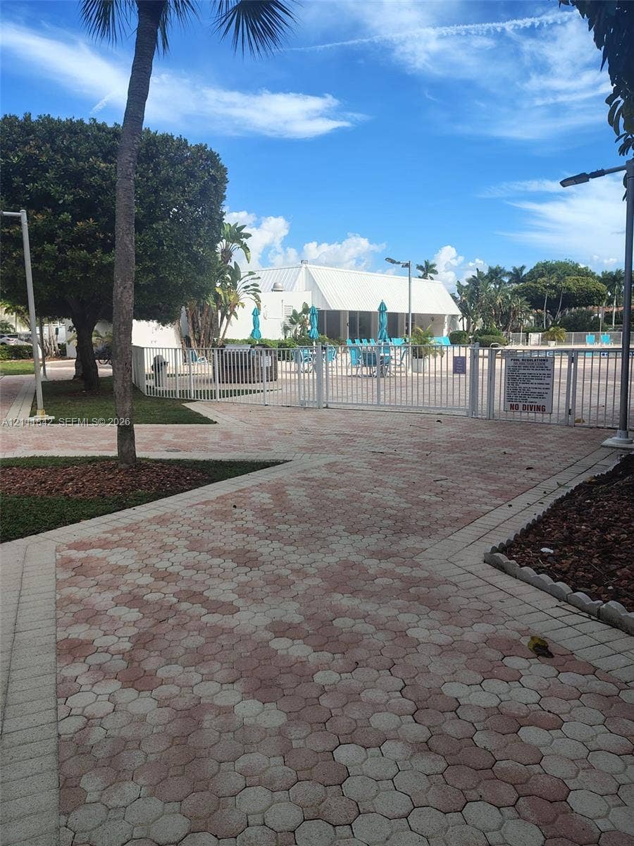 20400 W Country Club Drive, #303, Aventura, Aventura, FL 33180 Paver walkway featuring geometric pattern masonry leading to a fenced swimming pool area with mature landscaping