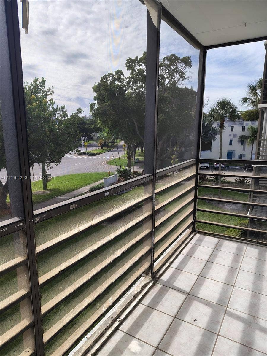 20400 W Country Club Drive, #303, Aventura, Aventura, FL 33180 Screened-in balcony featuring ceramic tile flooring, horizontal metal railings, and a metal frame enclosure