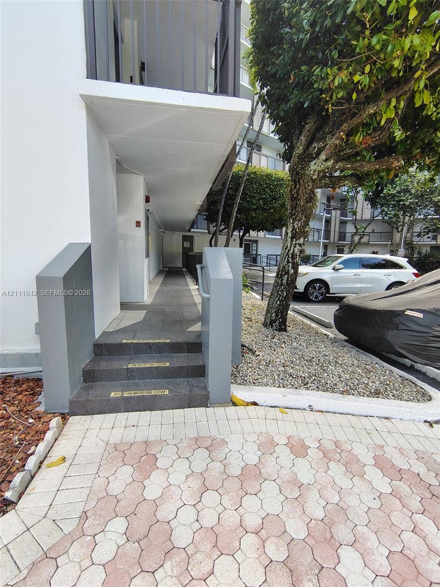 20400 W Country Club Drive, #303, Aventura, Aventura, FL 33180 Exterior walkway featuring grey tile steps, concrete sidewalls, and a covered pedestrian path