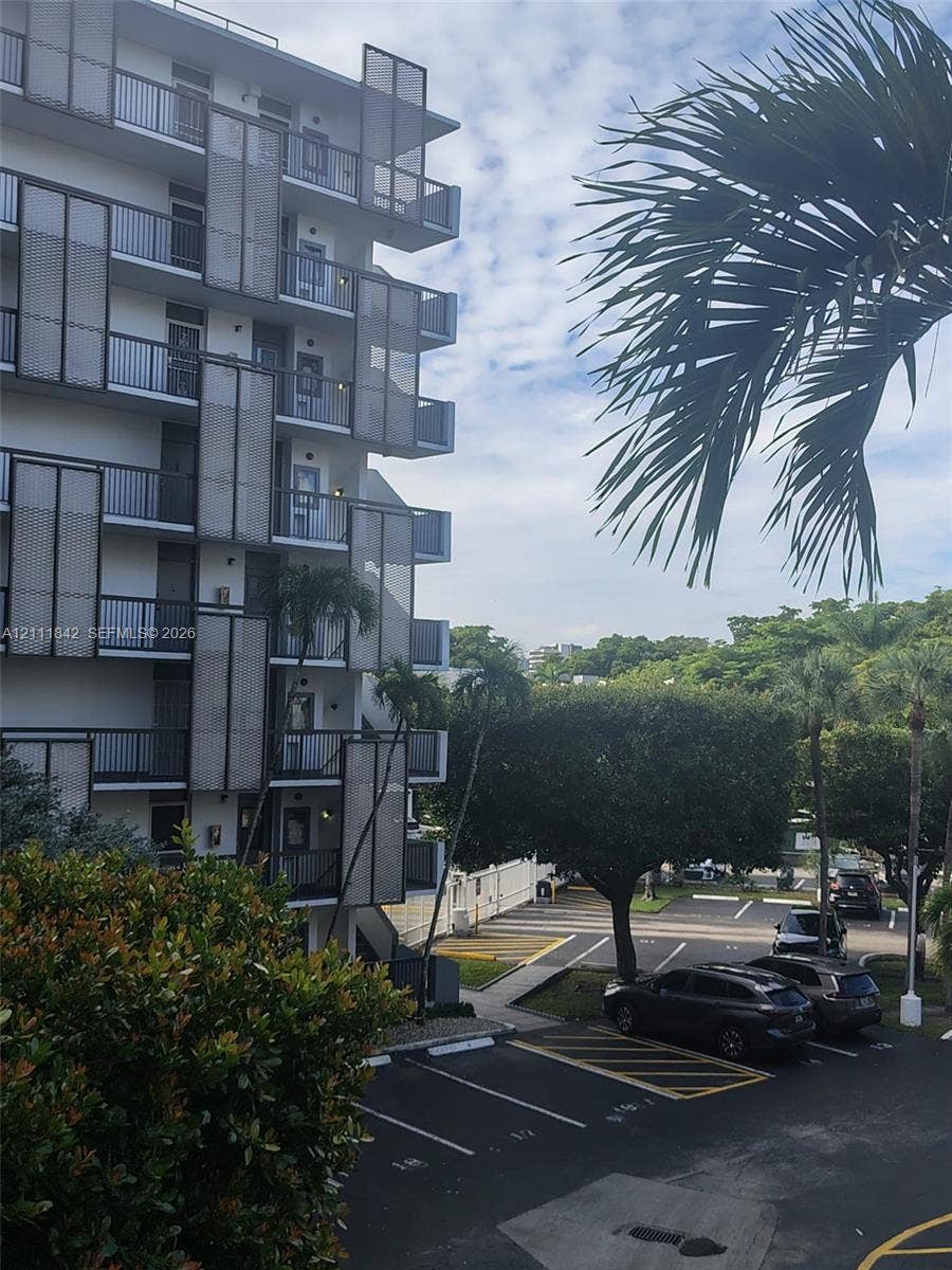 20400 W Country Club Drive, #303, Aventura, Aventura, FL 33180 Multi-story building exterior featuring dark metal grid balcony privacy screens, private balconies, and asphalt surface parking lot