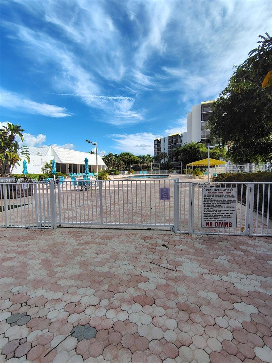 20400 W Country Club Drive, #303, Aventura, Aventura, FL 33180 Community swimming pool area featuring paved decking, metal perimeter fencing, and a covered pavilion