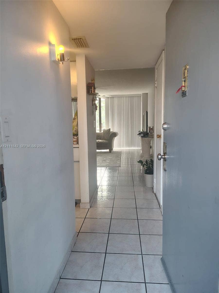 20400 W Country Club Drive, #303, Aventura, Aventura, FL 33180 Entryway featuring neutral-toned tile flooring, wall-mounted sconce lighting, and white interior doors
