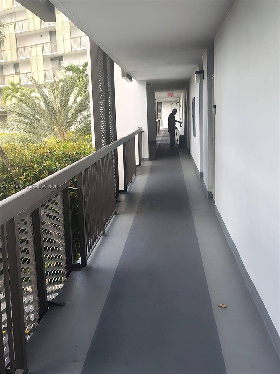 20400 W Country Club Drive, #303, Aventura, Aventura, FL 33180 Exterior corridor featuring painted concrete flooring, metal railings with decorative mesh panels, and wall-mounted exterior lighting