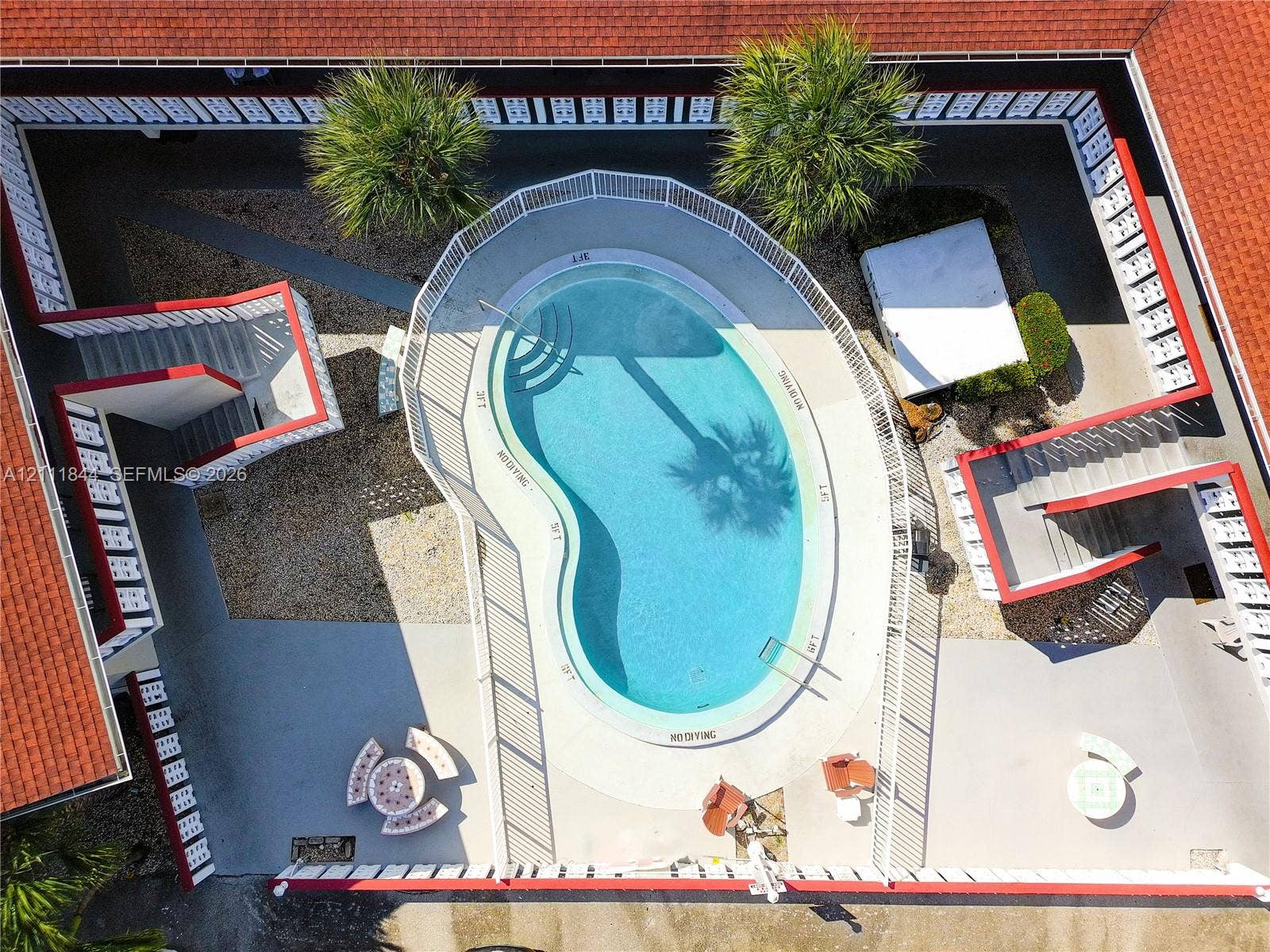 Courtyard featuring a kidney-shaped swimming pool, encircling metal railings, concrete decking, and red tile roofing