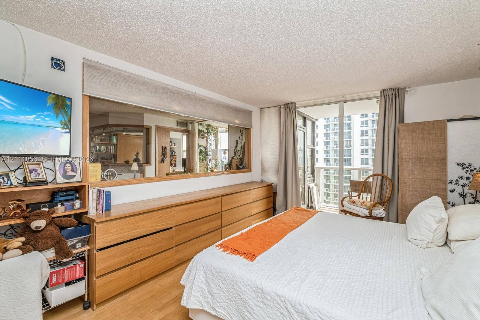6423 Collins Avenue, #1602, Miami Beach, FL 33141 Wood-finish flooring, built-in wooden cabinetry, expansive wall mirror, and floor-to-ceiling glass door providing outdoor access