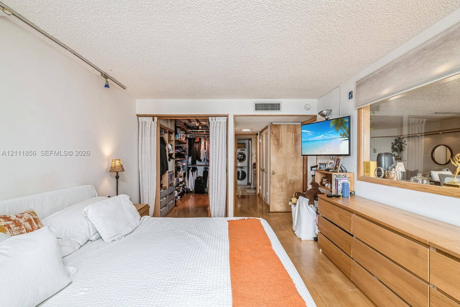 6423 Collins Avenue, #1602, Miami Beach, FL 33141 Bedroom featuring wood-finish flooring, built-in closet shelving, and a large interior glass window pane