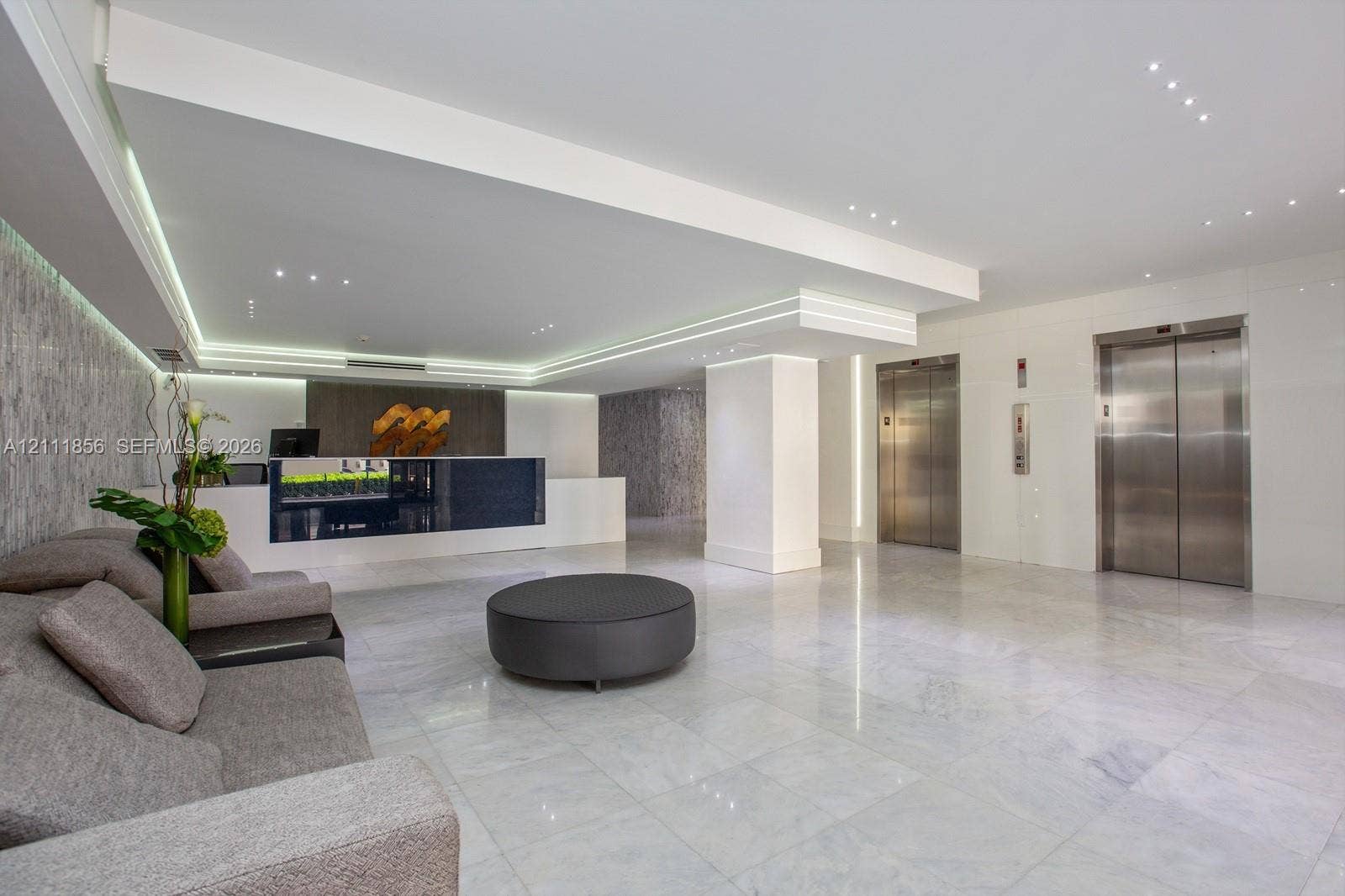 6423 Collins Avenue, #1602, Miami Beach, FL 33141 Lobby area featuring polished stone flooring, recessed ceiling lighting, cove accent lighting, stainless steel elevator doors, and a built-in reception desk