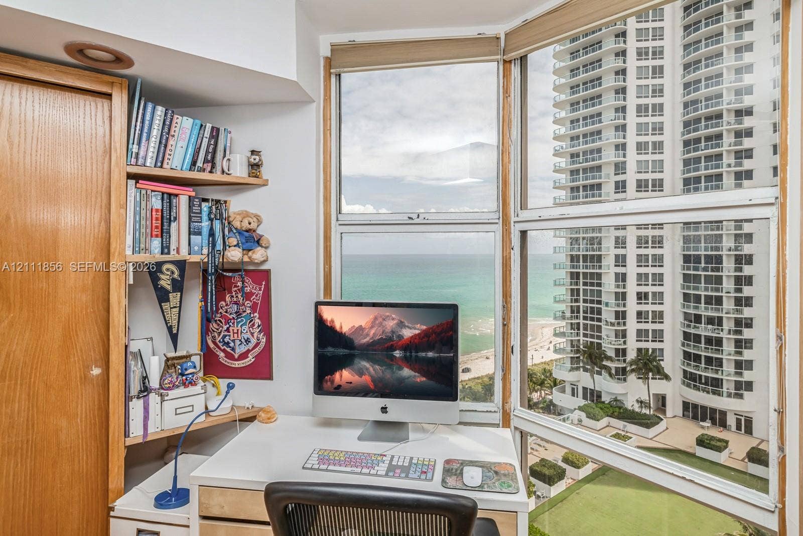 6423 Collins Avenue, #1602, Miami Beach, FL 33141 Floor-to-ceiling windows, built-in wooden shelving, and panoramic coastal scenery